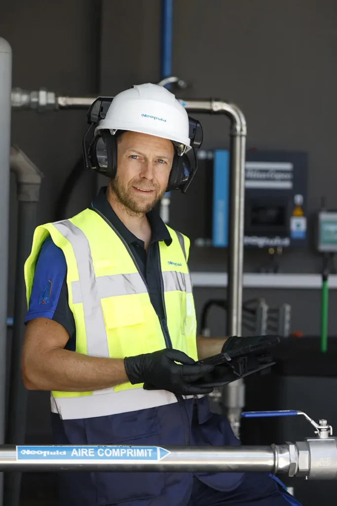 Tècnic de Neofluid revisant un sistema d'aire comprimit en una instal·lació industrial. Serveis integrals.