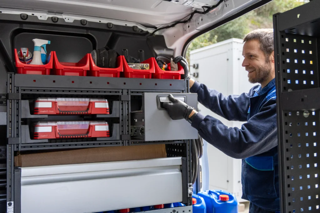 Dona gran somriuent amb el cabell curt, ulleres i top blau fosc, mirant a la càmera, expressant confiança i professionalitat amb un fons desenfocat.